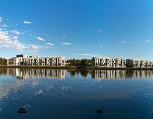 Beautiful view of a river with reflections of modern apartment buildings, blue sky and trees on water, Parramatta river, Wilson Park, Silverwater, Sydney, New South Wales, Australia
