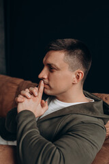 Portrait of a guy. Young man in a sweatshirt with a hood. Black background.
