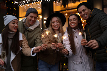 Group of happy friends with sparklers and champagne at winter fair