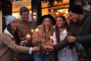Group of happy friends with sparklers and champagne at winter fair