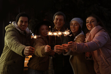 Group of happy friends with sparklers and champagne at winter fair