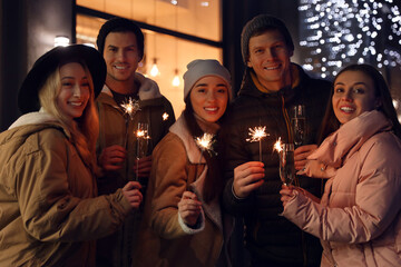 Group of happy friends with sparklers and champagne at winter fair
