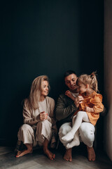 Photoshoot of a happy young family. Dad, mom and daughter. Studio photography.