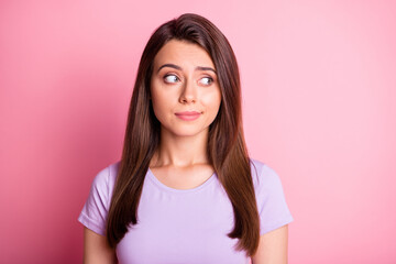Photo portrait of sceptical woman looking to side isolated on pastel pink colored background