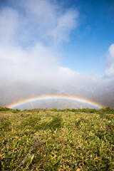 It is a mountain range of Hakuba in Nagano prefecture, Japan. There is a rainbow in the valley of the mountains. It is a very beautiful photo under the blue sky.