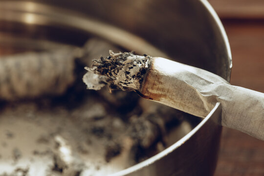 Lighted cigarette in a metal ash tray close up