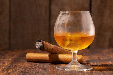 Glass of whisky and lighted cigar in an ash tray