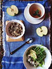 delicious breakfast: a cup of tea with lemon, porridge and green salad on a denim tablecloth