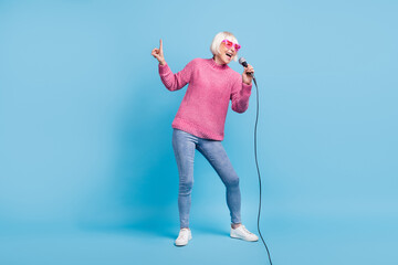 Photo portrait full body view of elderly lady singing pointing finger up holding mic in one hand...