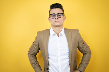 Young business man over isolated yellow background skeptic and nervous, disapproving expression on...