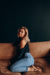 Photoshoot of a blonde in a black bra and jeans. Studio photography.