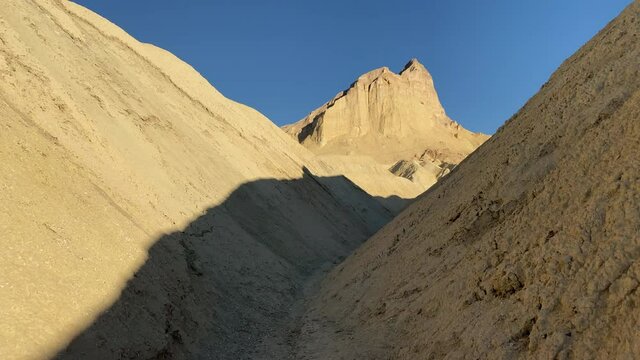 Walking between the sandstone hills toward Manley Beacon at Golden Canyon at Death Valley National Park, CA, USA. Move in. Tracking.