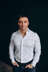 Portrait of a guy. Young man in a white shirt. Black background.