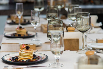 Pancakes are decorated with blackberries and raspberry jam on a plate. Served table in restaurant. Breakfast.