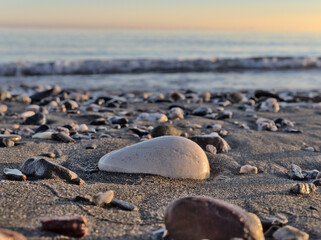 Closeup Pebbles stones on sand at the beach with the sea at background. selective focus