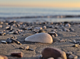 Closeup Pebbles stones on sand at the beach with the sea at background. selective focus