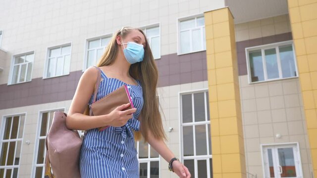 A girl in a medical mask in the Park. A young girl student goes to College for classes in a mask. Personal protective equipment disease Prevention.An outbreak of the coronavirus epidemic.