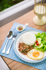 Basil Fried Rice with Pork and Fried Egg on white plate serving on table