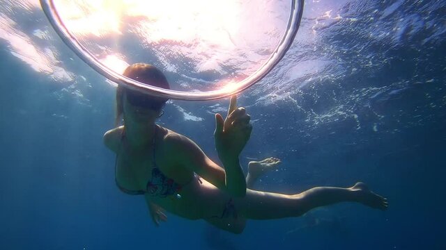 Ring bubble and woman in bikini. Young woman freediver plays with ring bubble moving in the depth of a sea. Underwater extremely slow motion scene