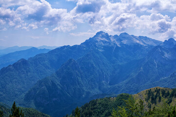 Summer landscape – beautiful Albanian mountains, covered with green trees and clouds on blue sky.