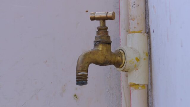Close shot of old brass metal water faucet tap with water dripping from it, water wastage concept