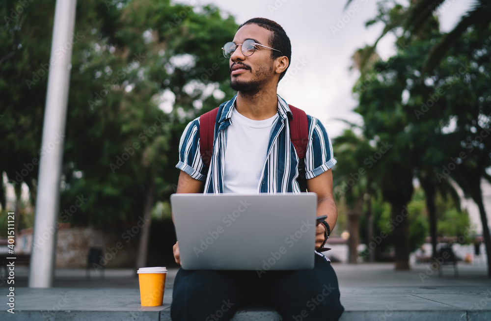 Wall mural focused young man with laptop working remotely in park