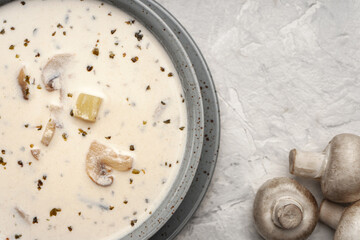 Vegetarian soup with coconut cream and mushrooms near raw champignons top view, close-up