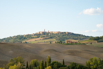 It is the scenery near Pienza in Tuscany, Italy. Agricultural land spreads out on the hill under the blue sky.