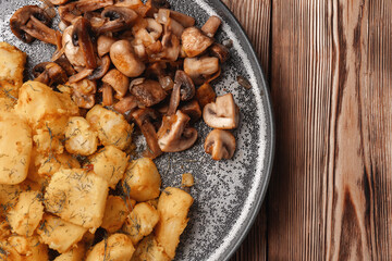 Fried potatoes near fried mushrooms on a gray plate top view, close-up
