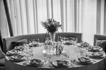 Luxury wedding banquet reception dinning table setup. The chairs and table for guests, decorated with flowers, served with cutlery and crockery and covered with a tablecloth.
