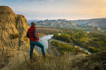 Male person stands on the edge and look right to sunrise with stunning landscape view of...
