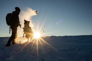 man and dog having fun in fresh snow