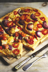 Fresh homemade focaccia with blue onions and cherry tomatoes.