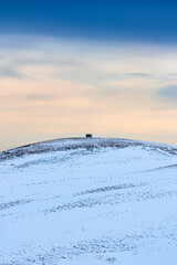 Small cabin on top of snowy hill 