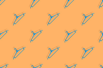 Clothes hanger on an orange background. Clothes hangers seamless pattern.