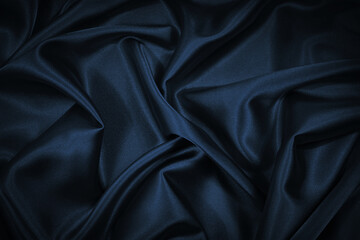 Black blue abstract background. Dark blue silk satin texture background. Beautiful wavy soft folds on the surface of the fabric. Navy blue elegant background with copy space for your design. Web banne