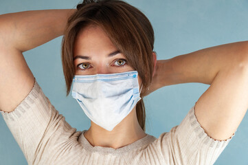 Young woman wearing blue disposable mouth face nose virus mask, closeup portrait, focus on her...