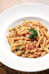 penne amatriciana tomato and ham sauce pasta on wood table
