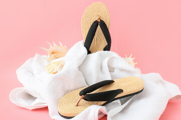 Stylish female flip-flops and towel on color background
