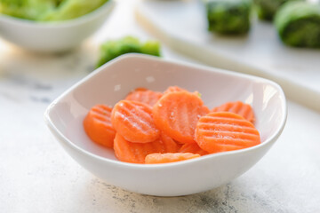 Frozen vegetables in bowl on light background