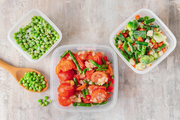 Frozen vegetables in plastic containers on light background