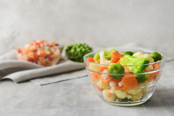 Frozen vegetables in bowl on light background