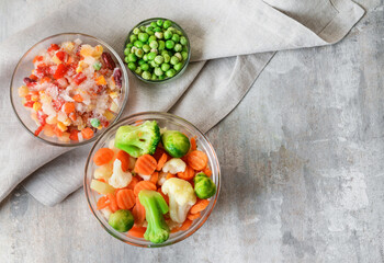 Frozen vegetables in bowls on light background