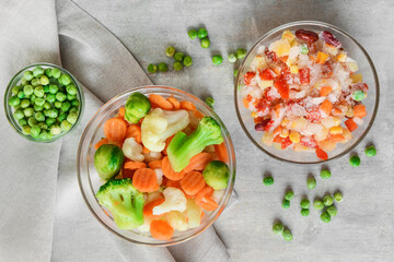 Frozen vegetables in bowls on light background