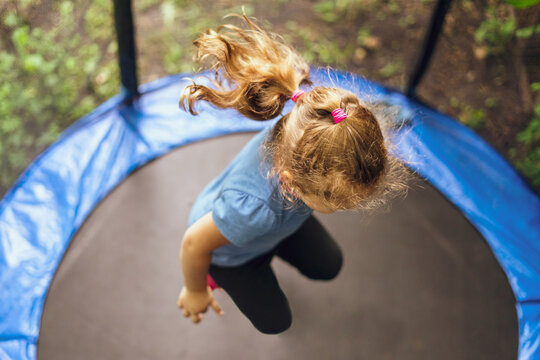 Little girl jumping on a trampoline on a summer day
