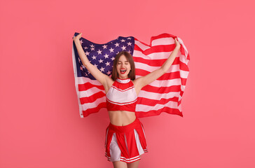 Beautiful young cheerleader with USA flag on color background