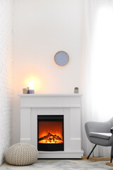 Fireplace with pouf and armchair in interior of room