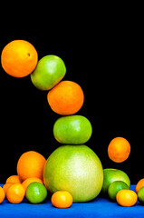 Falling tower of citruses, oranges, pummelo, limes, tangerines and grapefruits isolated on black background