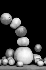 Monochrome falling tower of citruses, oranges, pummelo, limes, tangerines and grapefruits isolated on black background