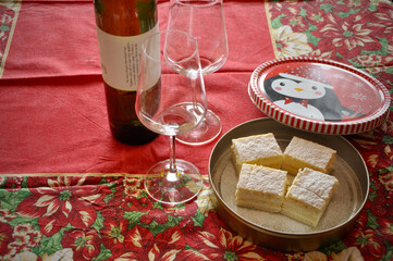 Christmas decorated table with cake slice and vine glasses. Piece of white cake slice close up homemade